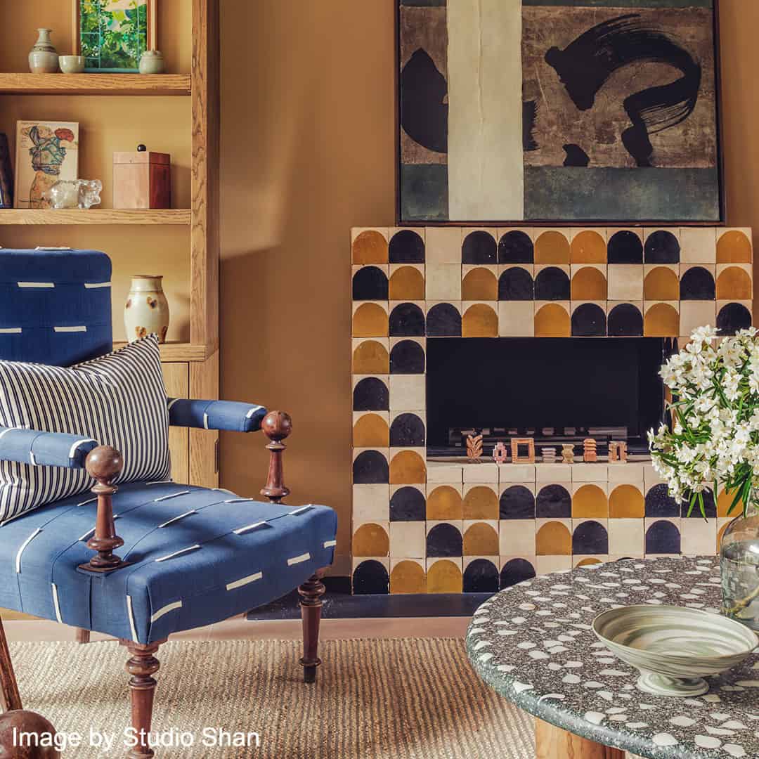 Living room with blue upholstered chair, patterned fireplace, and decorative elements.