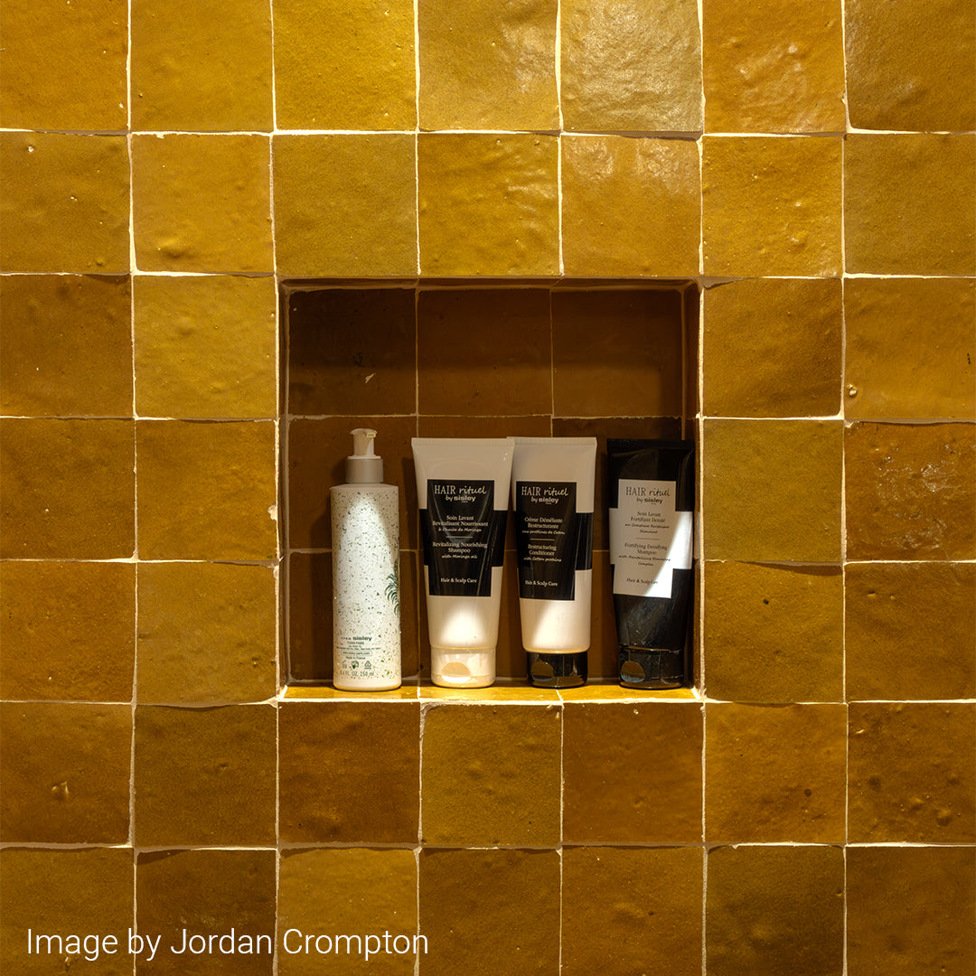 Bathroom niche with skincare products against a yellow tiled wall