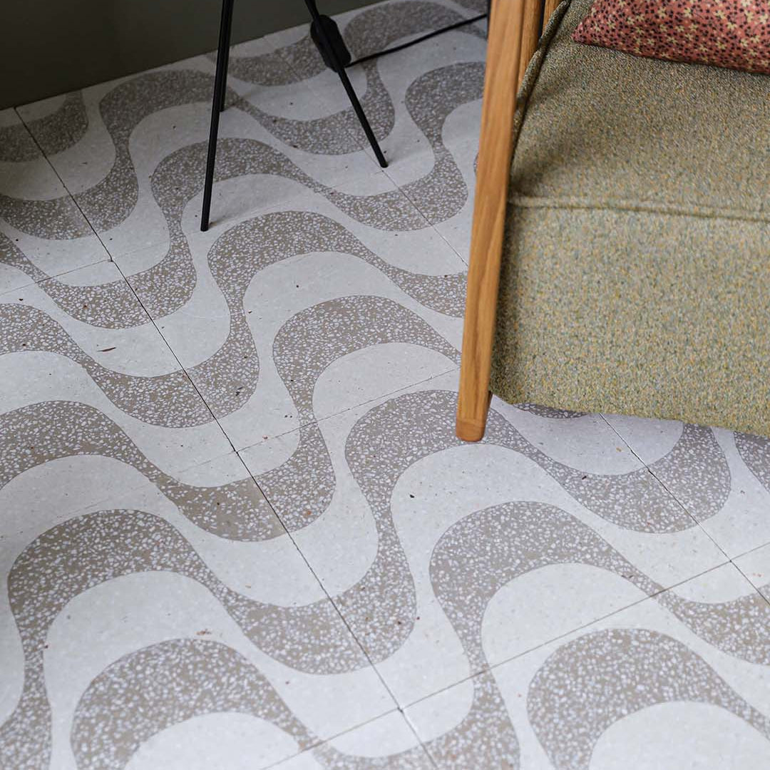 Beige and white terrazzo-style cement tile featuring curved wave patterns with speckled stone textures, ideal for modern interiors, accent walls, or contemporary geometric floor designs.