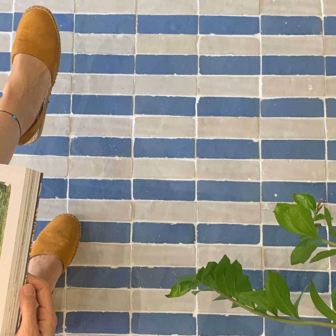 Person wearing mustard yellow shoes on a blue and white tiled floor with a plant in the foreground.