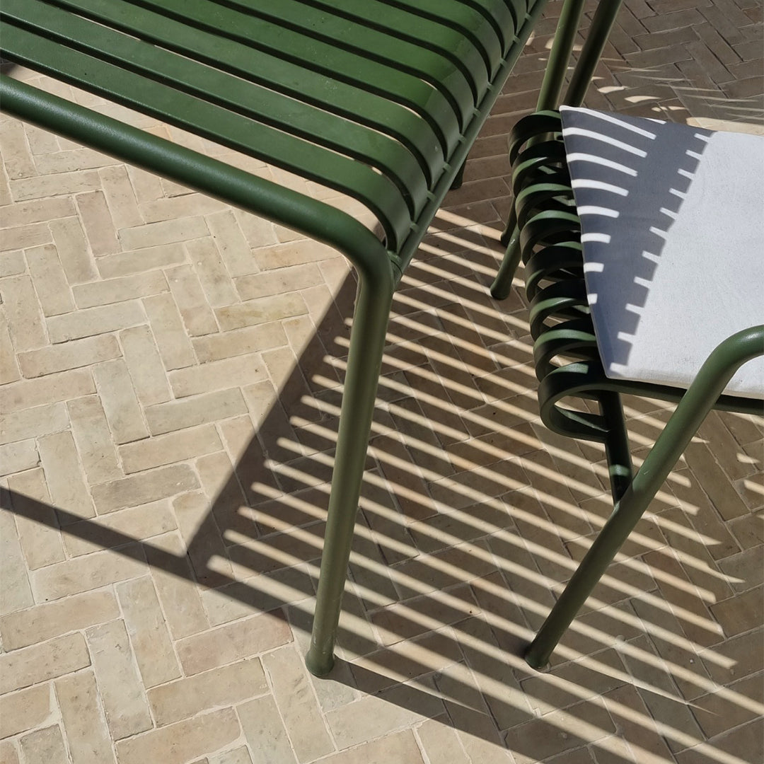 Light herringbone bathroom tile flooring with green chairs casting artistic shadows, blending modern furniture and interior design.