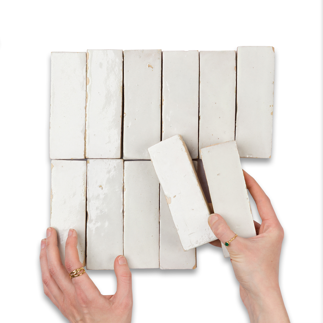 Hands holding two white soap bars over a grid of additional soap bars on a white background
