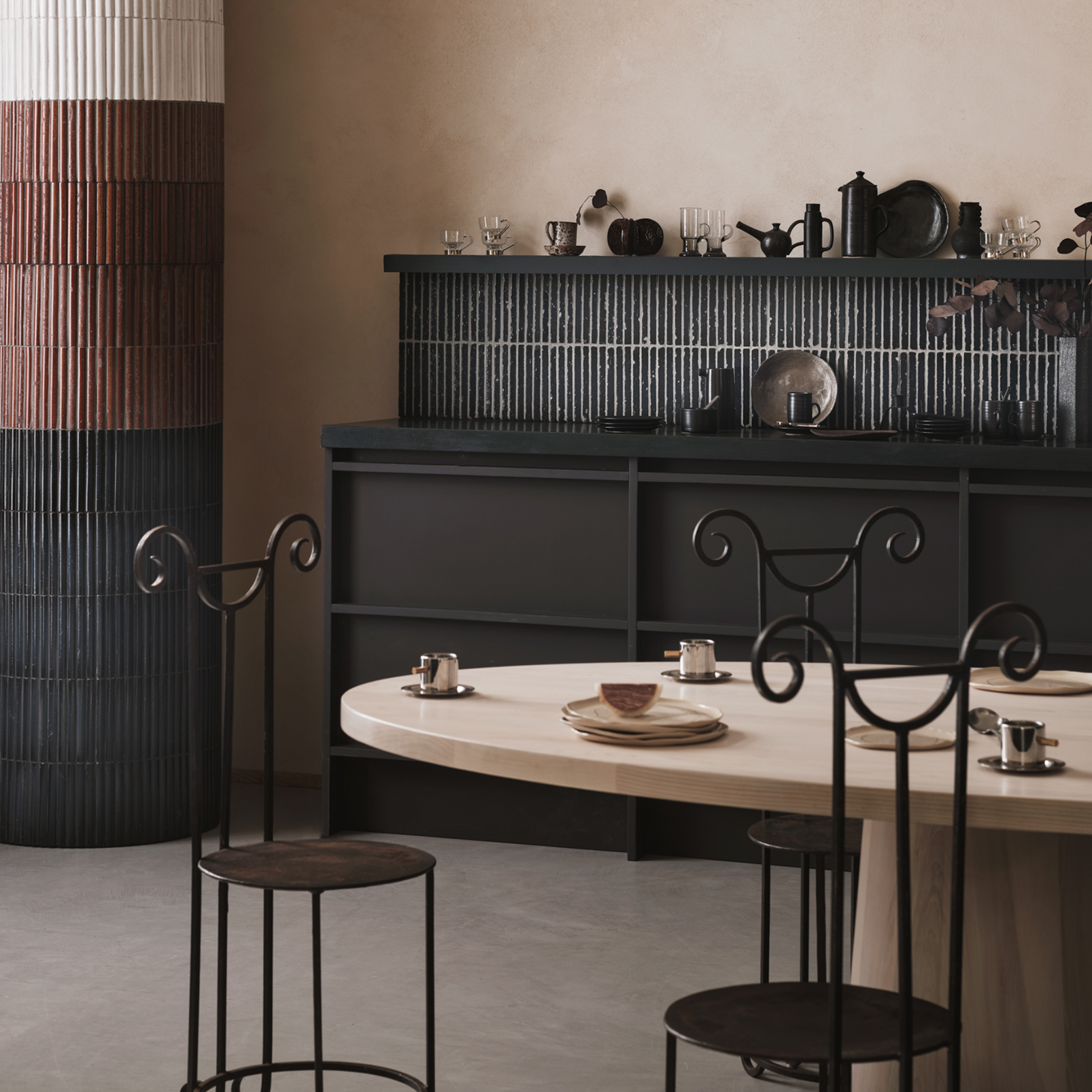 Dining area with a round table and chairs against a neutral wall.