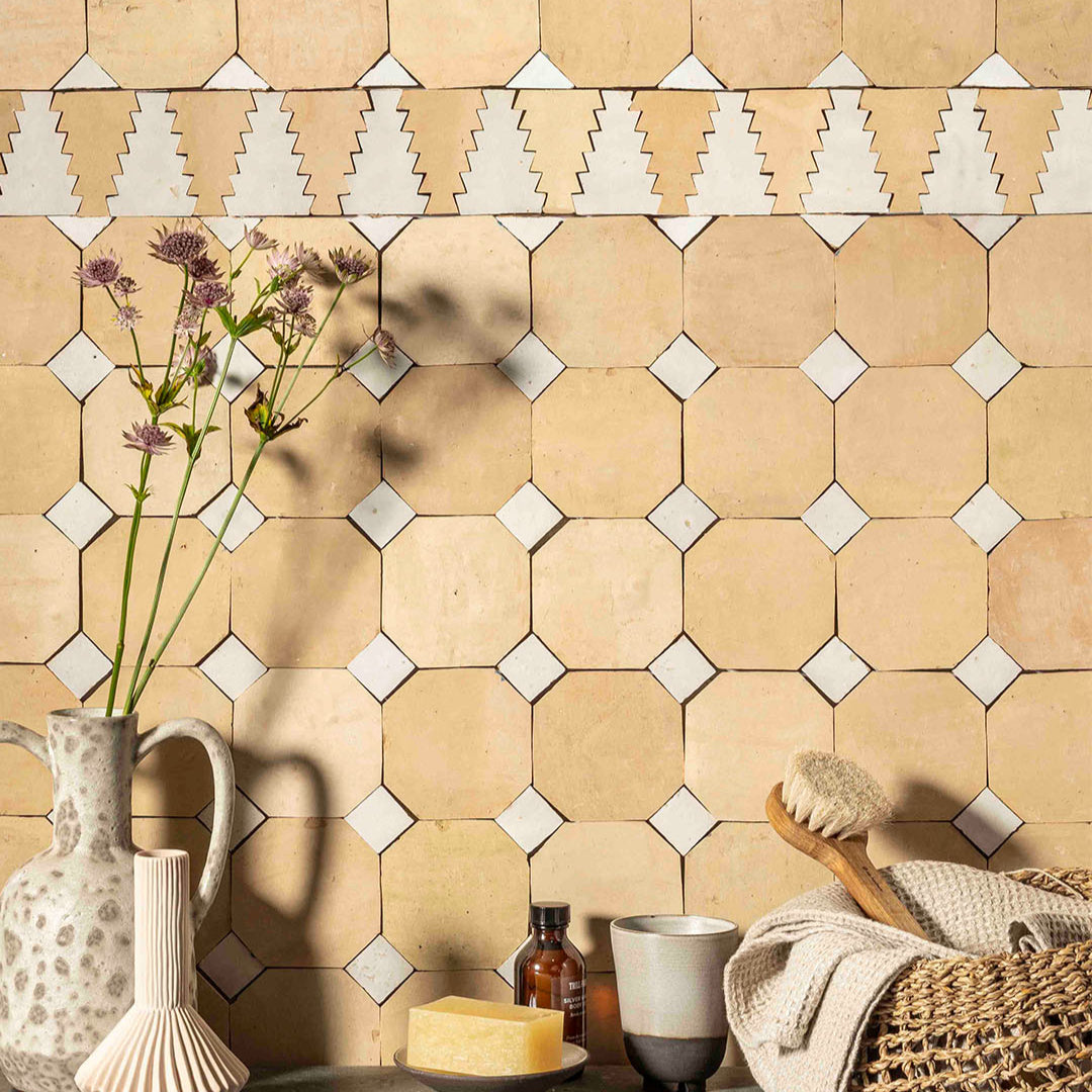 Beige hexagonal tiles with white accents on a wall, with decorative items like a vase and candle.