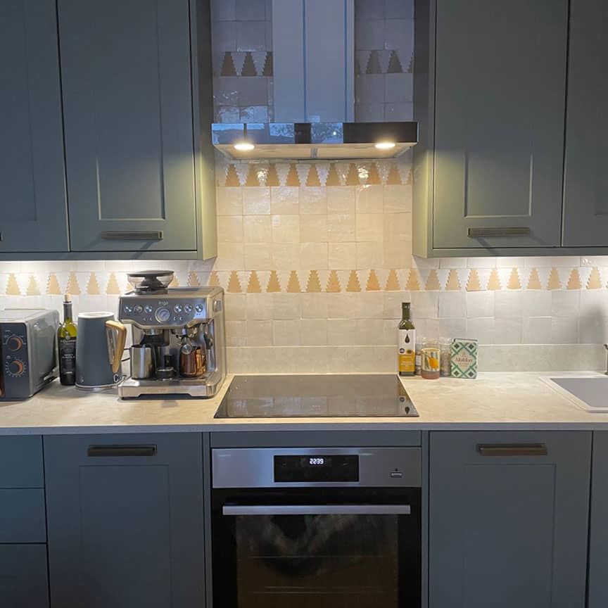 Modern kitchen with gray cabinets, stainless steel appliances, and a backsplash.