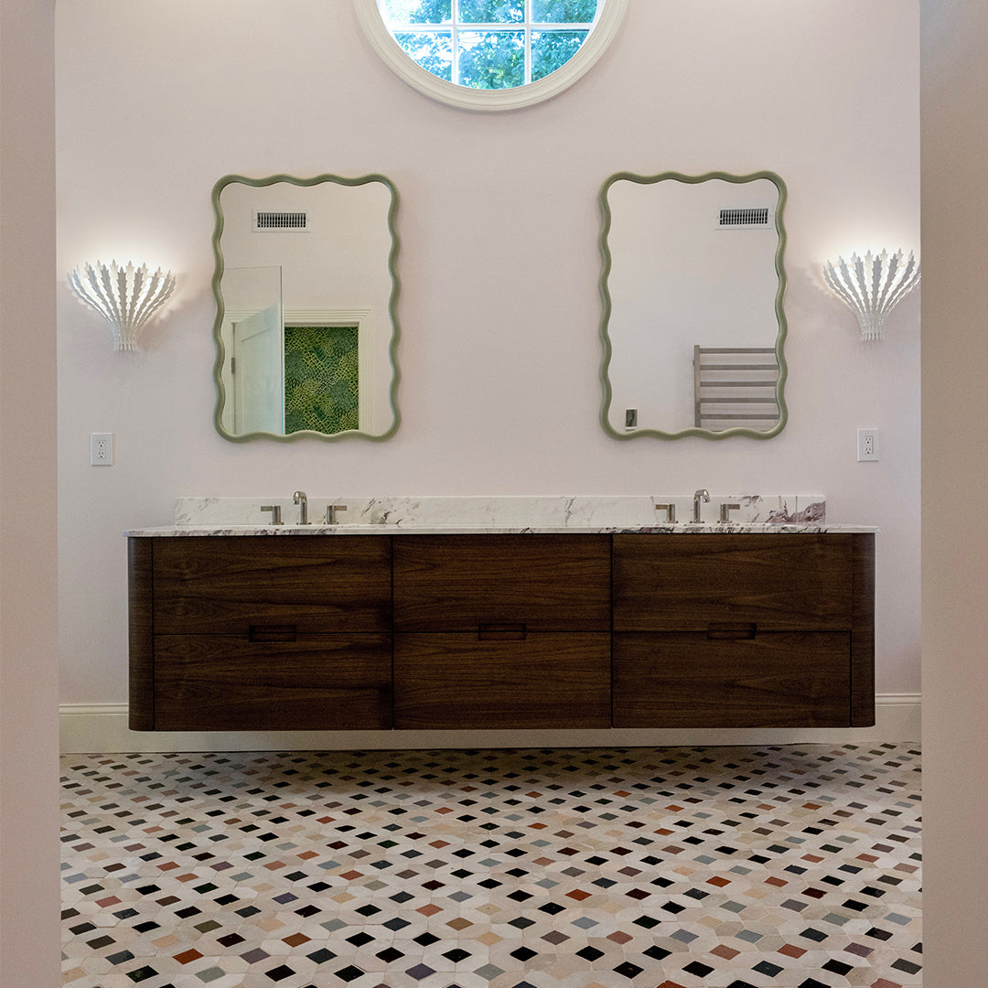 Bathroom with wooden vanity, mirrors, and patterned floor.