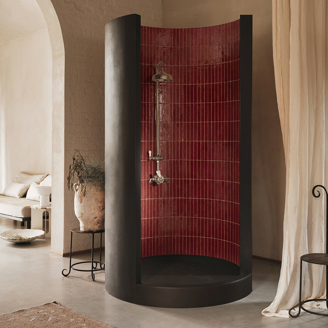Modern shower enclosure with red tiled wall in a bathroom setting