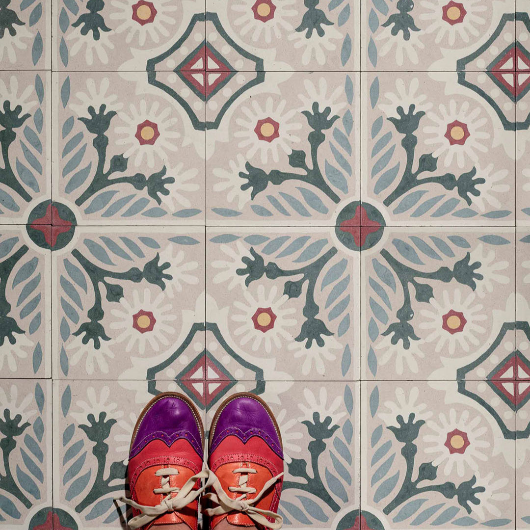 A floral pattern with white daisy-like flowers, green stems, and blue-gray leaves on a beige background, accented with red and yellow details, ideal for vintage or Mediterranean interiors.