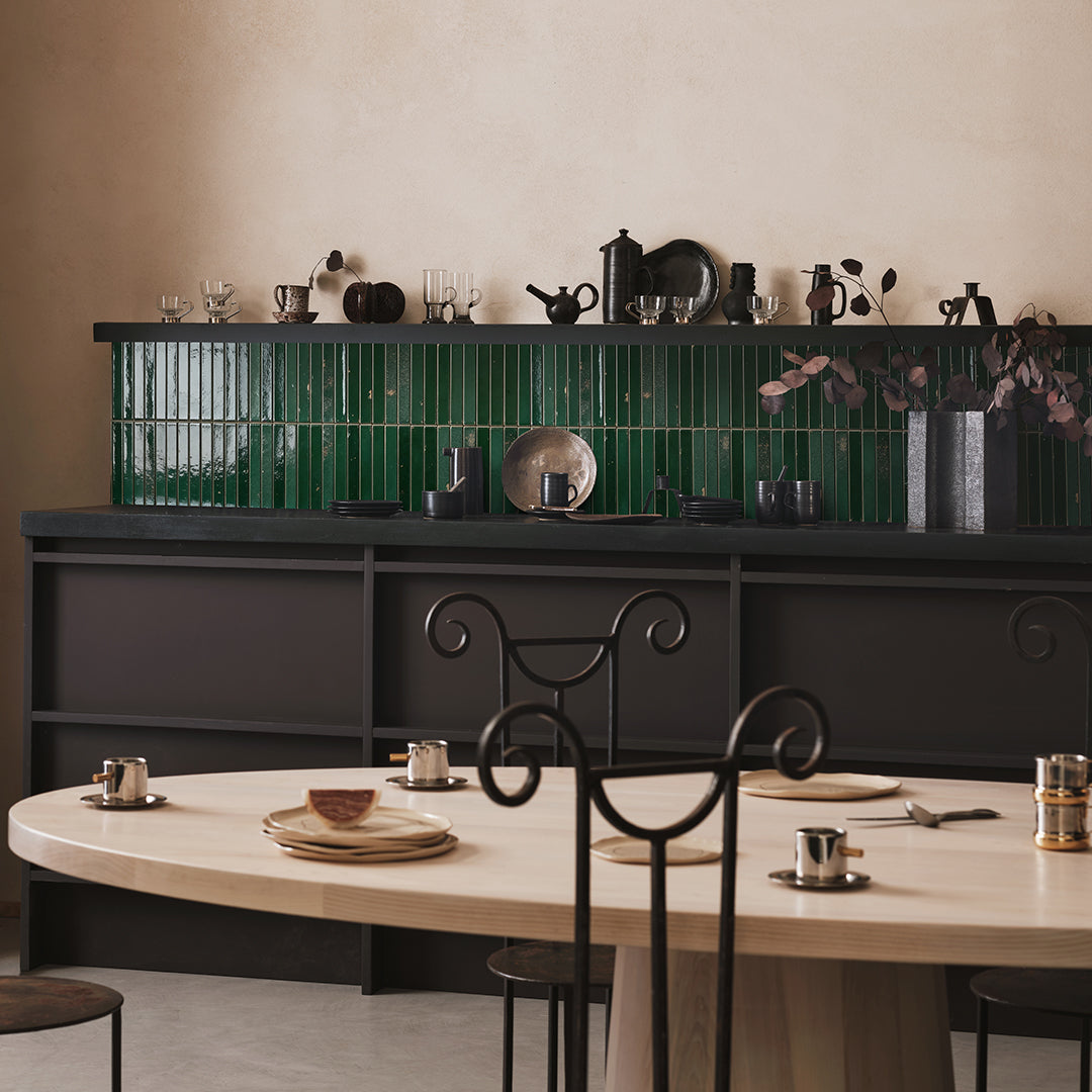 Dining area with a table and chairs in front of a dark wall with decorative elements.