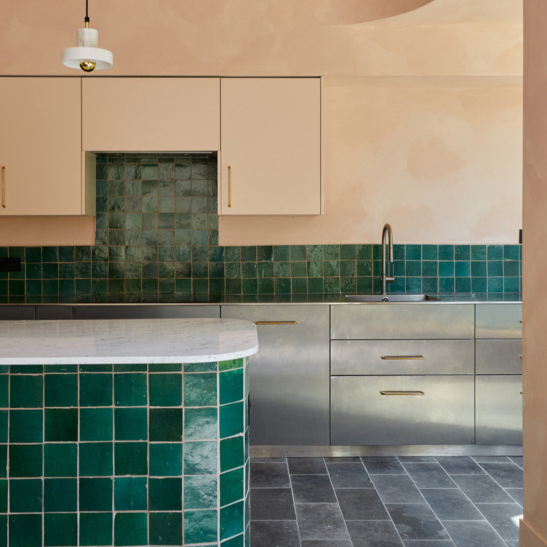 Modern kitchen with green tiled backsplash and gray floor.