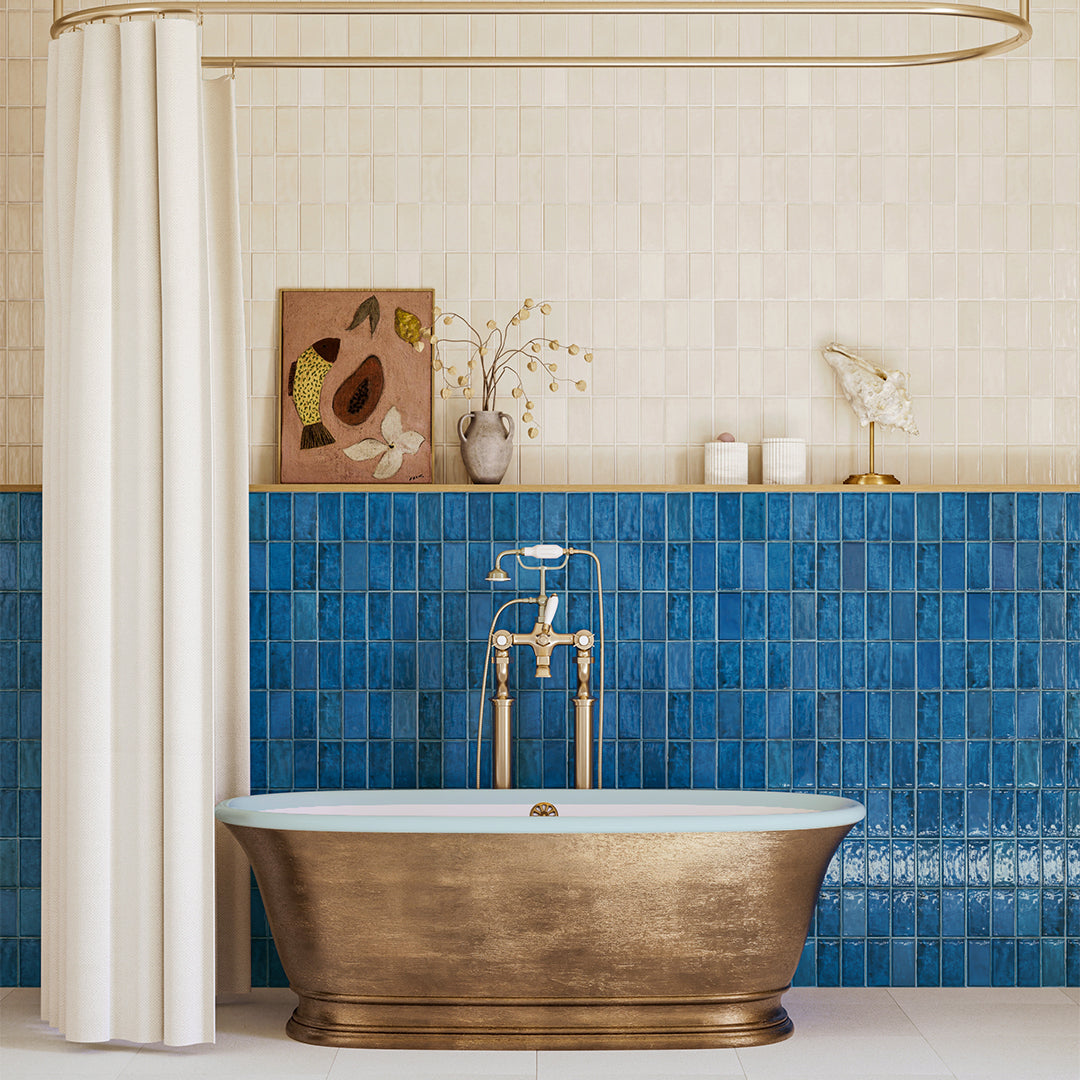 Bathroom with a gold freestanding bathtub against a blue tiled wall.