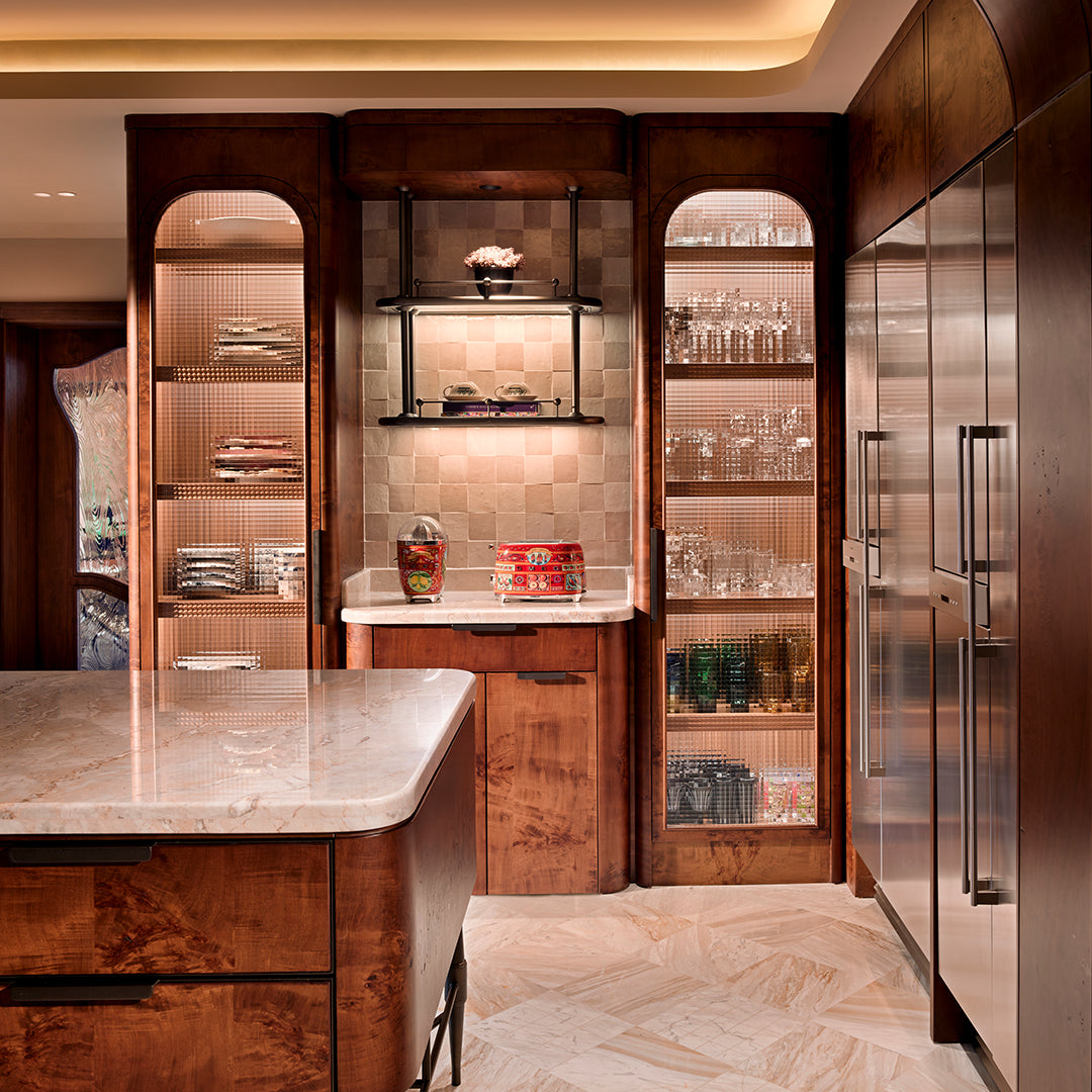 Modern kitchen with wooden cabinets, marble island, and stainless steel refrigerator.