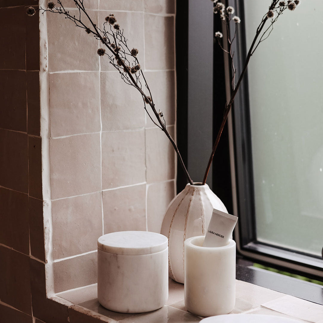Decorative setting with a vase and cylindrical containers on a windowsill.