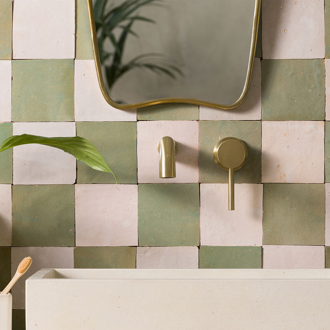 Bathroom setting with checkered tiles, gold fixtures, and a mirror.