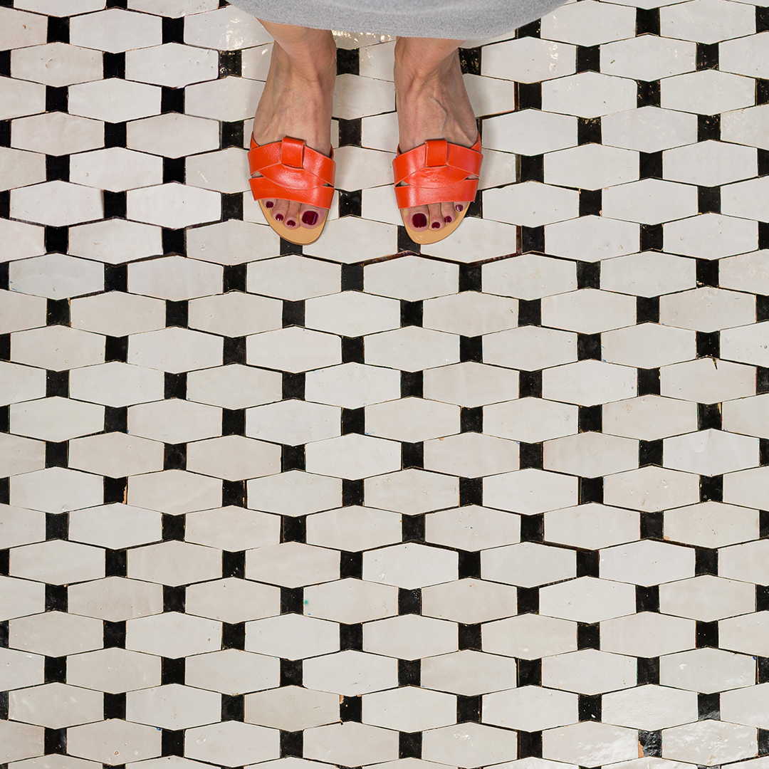 Person wearing red sandals on a black and white geometric tile floor
