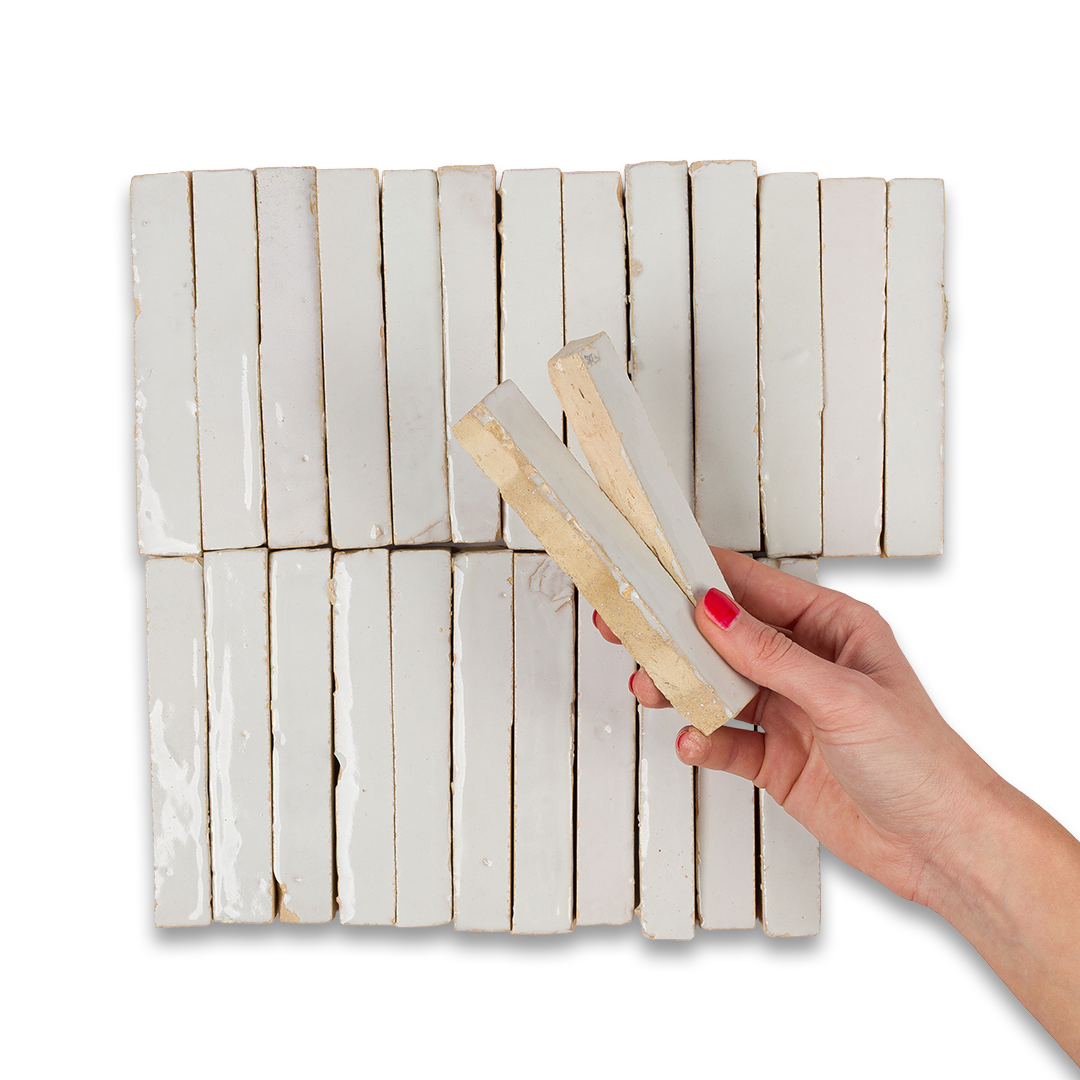 Hand holding a rectangular object over a white wooden panel with a grid pattern
