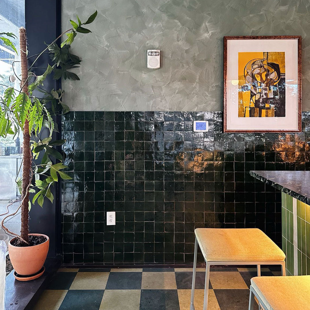 Modern interior with black tiled wall, plant, and abstract art.