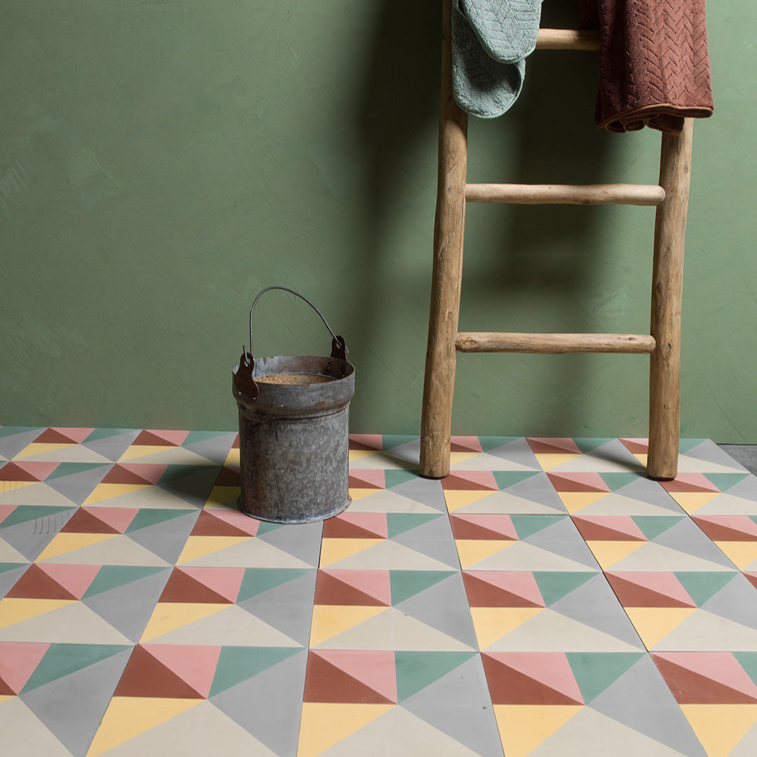 Cement tile featuring a geometric pinwheel pattern with pastel grey, yellow, green, pink, and terracotta triangles, matte finish, ideal for modern, mid-century, or eclectic interior flooring and wall décor applications.