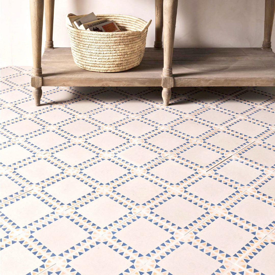 Square cement tile featuring a cream base with a geometric border of alternating blue and terracotta triangles, handcrafted matte finish, ideal for Mediterranean, bohemian, or contemporary interior flooring and wall décor.