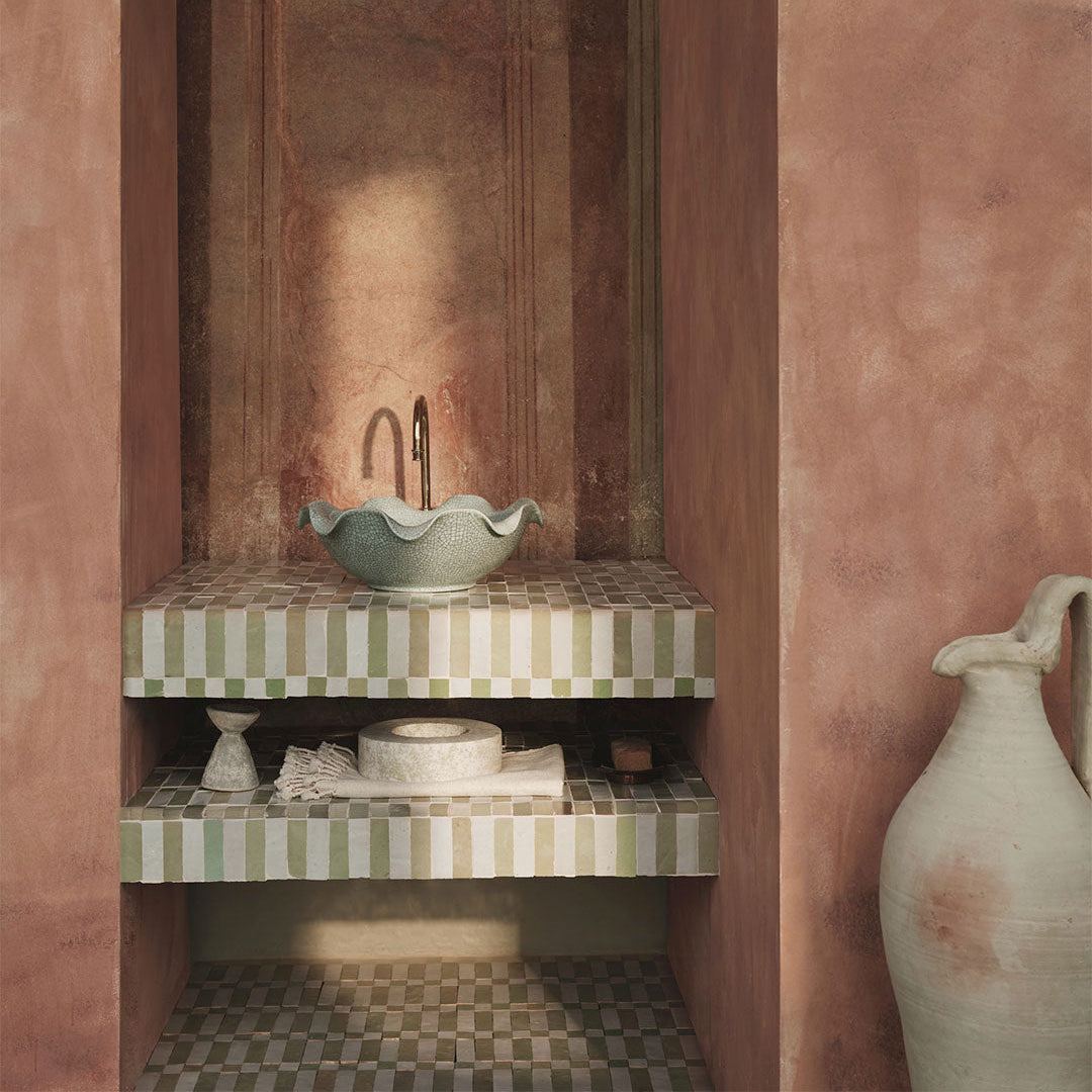 Bathroom with pink walls, checkered tiles, and a green sink.
