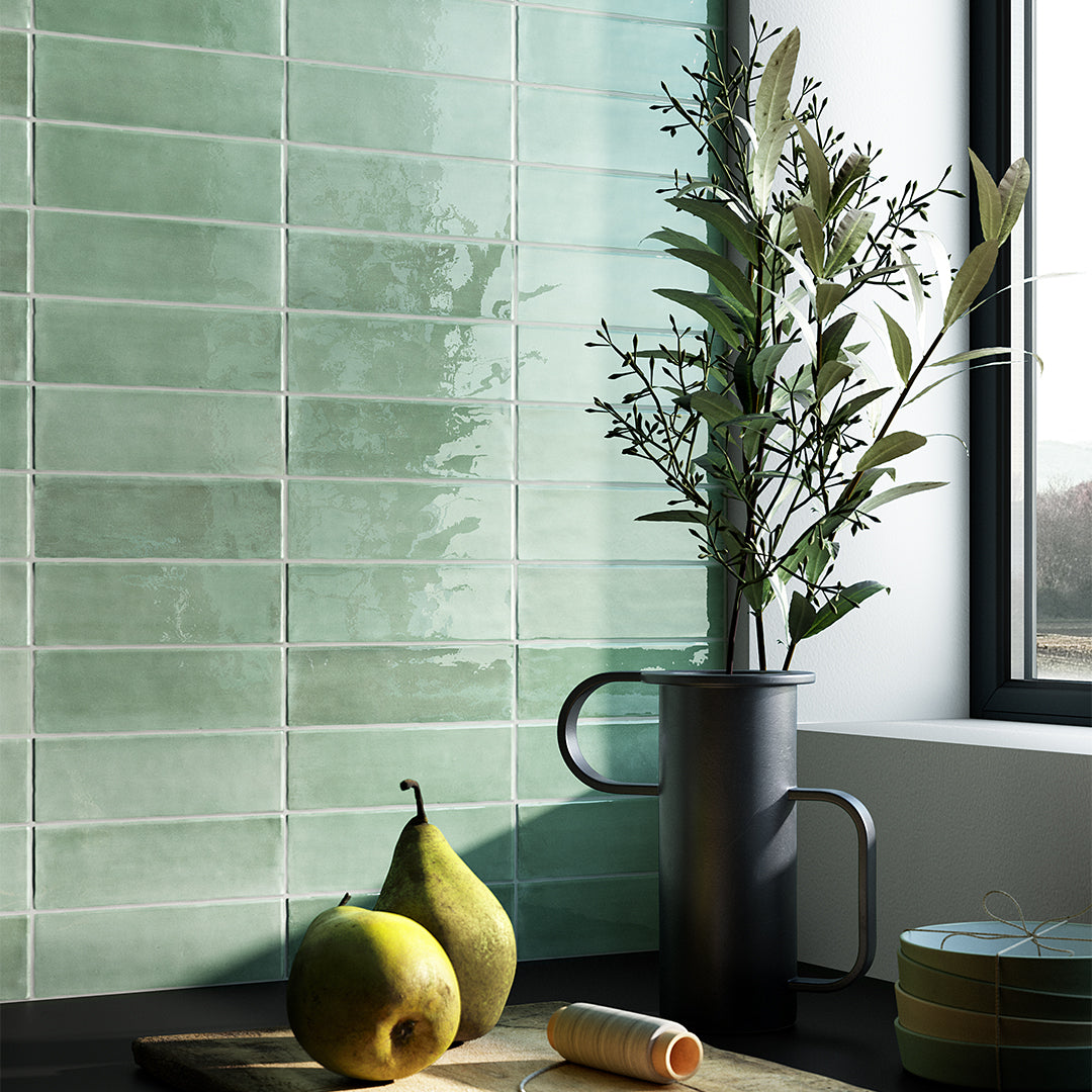 Green tiles on a wall with pears and a plant in a pot.