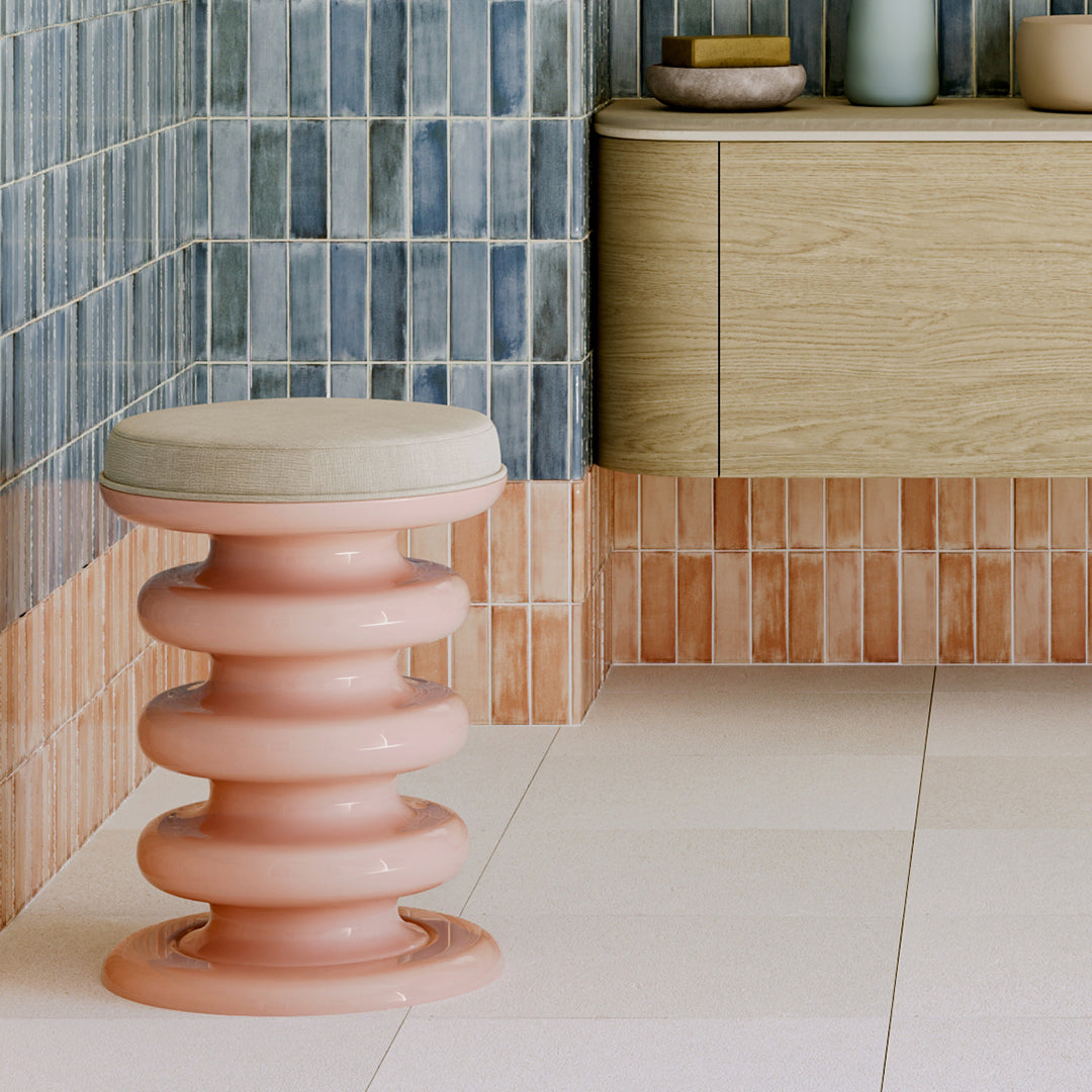 Pink stool with a cushioned seat in a tiled bathroom
