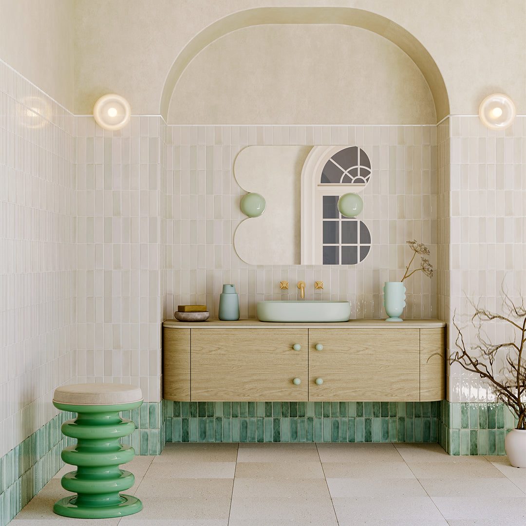 Bathroom with wooden vanity, green tiles, and decorative elements.
