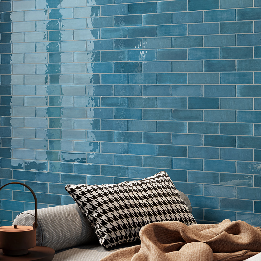 Blue tiled wall with a cushion and blanket in front