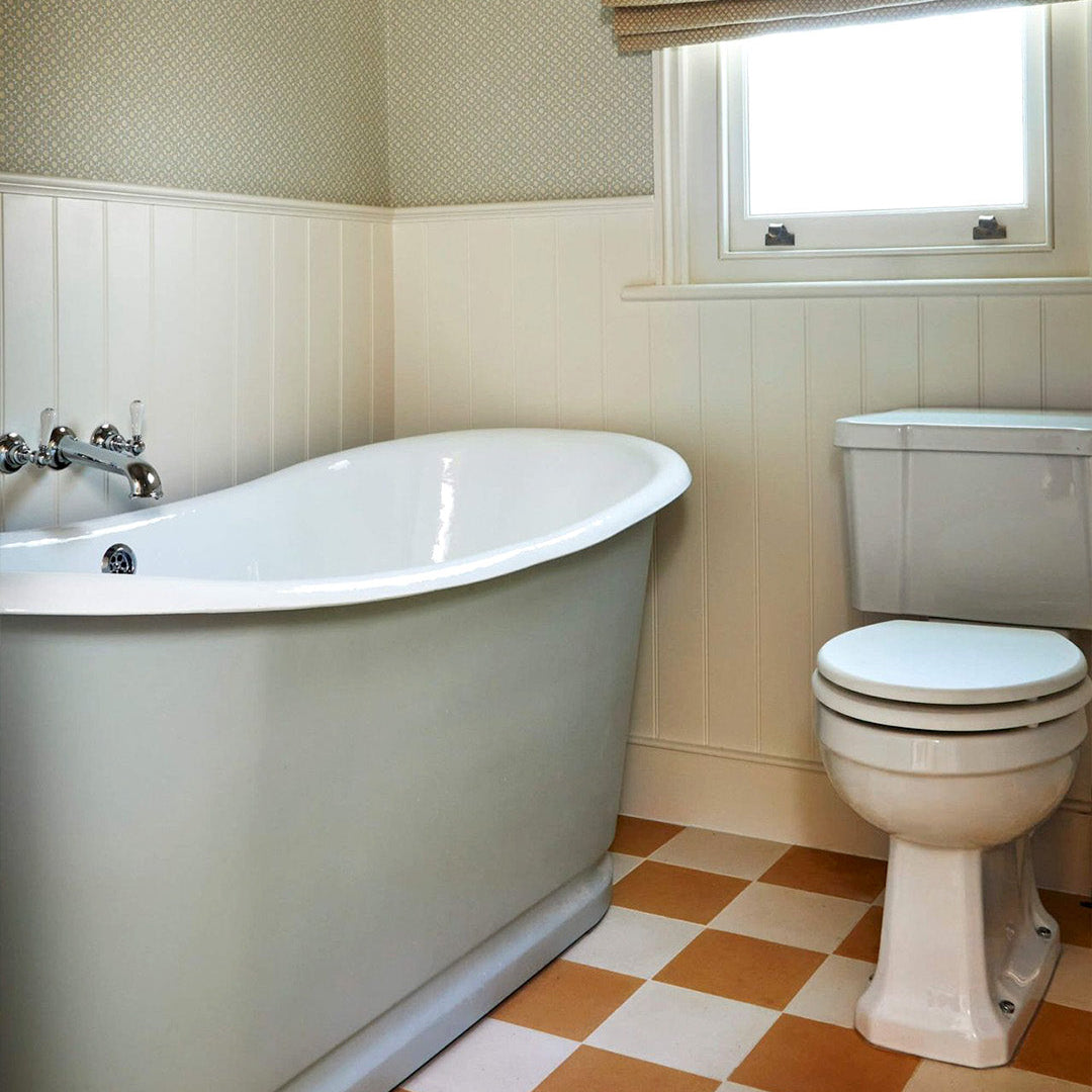 Bathroom with freestanding bathtub and toilet on a cement tile featuring a solid melon orange color with a smooth matte finish, handcrafted surface, ideal for Mediterranean, tropical, or contemporary interior flooring and wall décor applications.