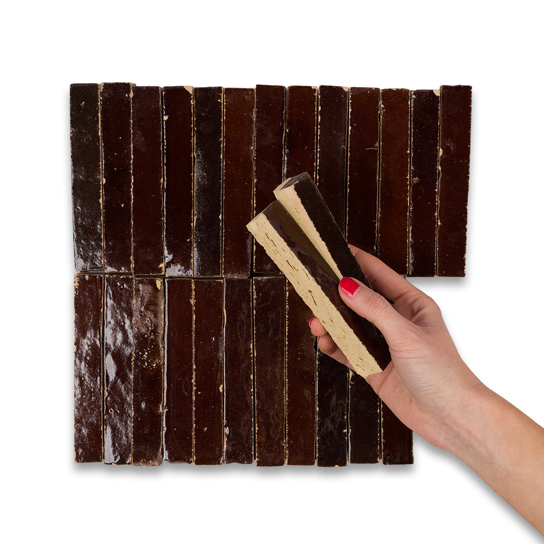 Hand holding a piece of brown tile against a background of chocolate bars