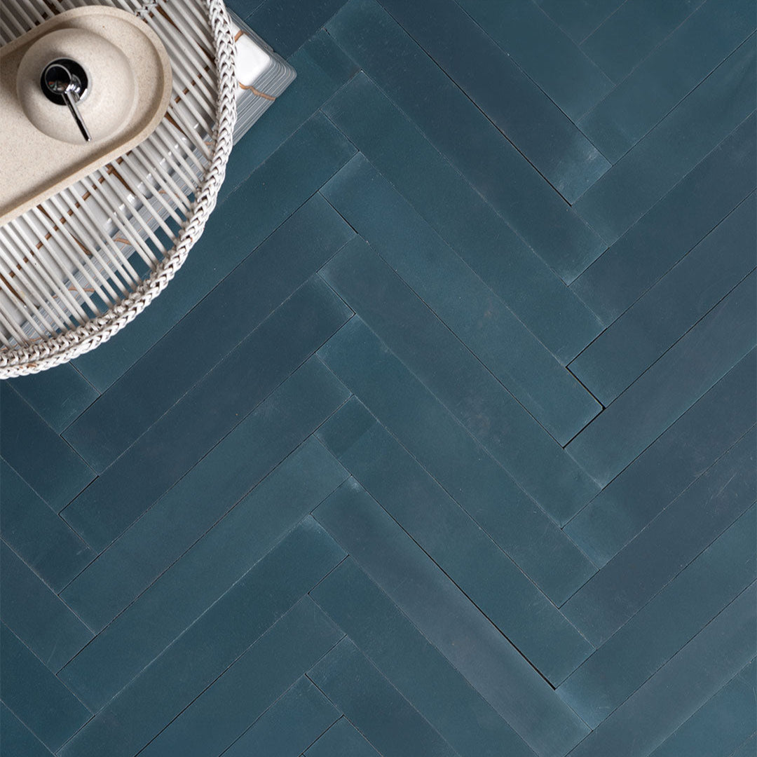 Cement tile featuring elongated rectangular strips in deep teal blue arranged in a herringbone pattern, matte finish, ideal for modern, coastal, or contemporary interior flooring and wall décor applications.
