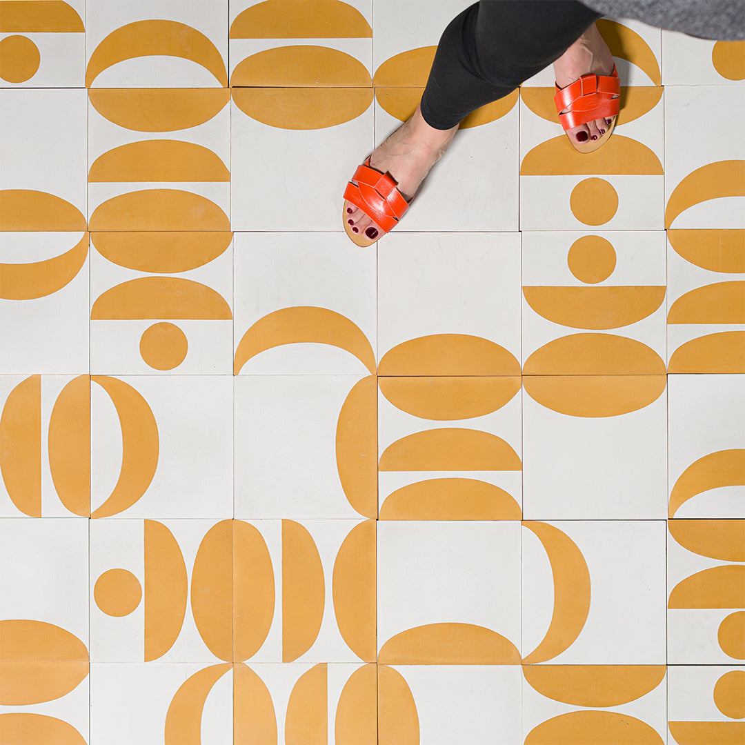 Cement tile featuring a geometric pattern of mustard yellow semicircles and curved shapes on a white background, matte finish, ideal for modern, retro, or mid-century interior flooring and wall décor applications.