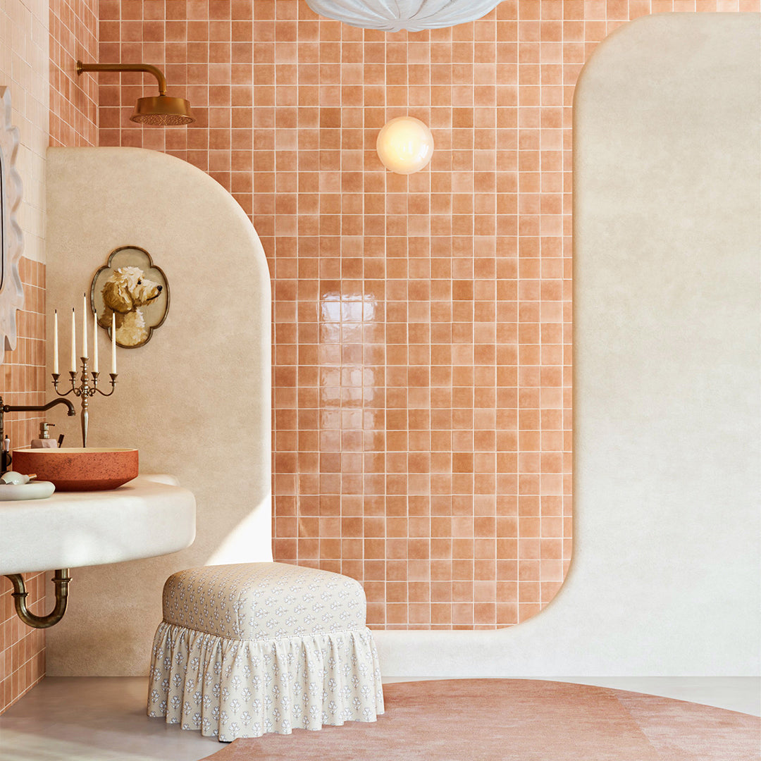 Bathroom with pink tiled walls, a sink, and a stool.