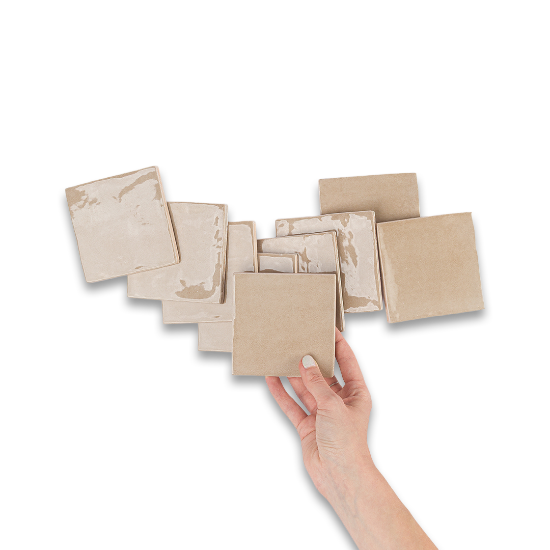Hand holding a beige square pad with multiple pads stacked behind on a white background