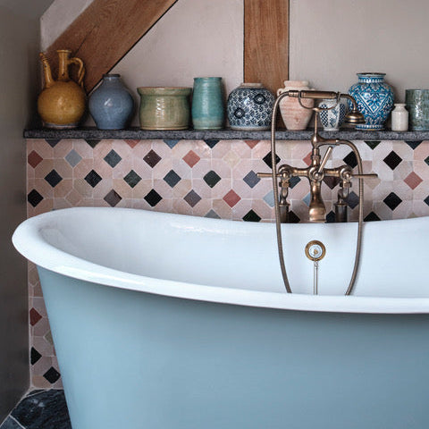 Bathroom with a freestanding bathtub, decorative tiles, and various vases on a shelf.