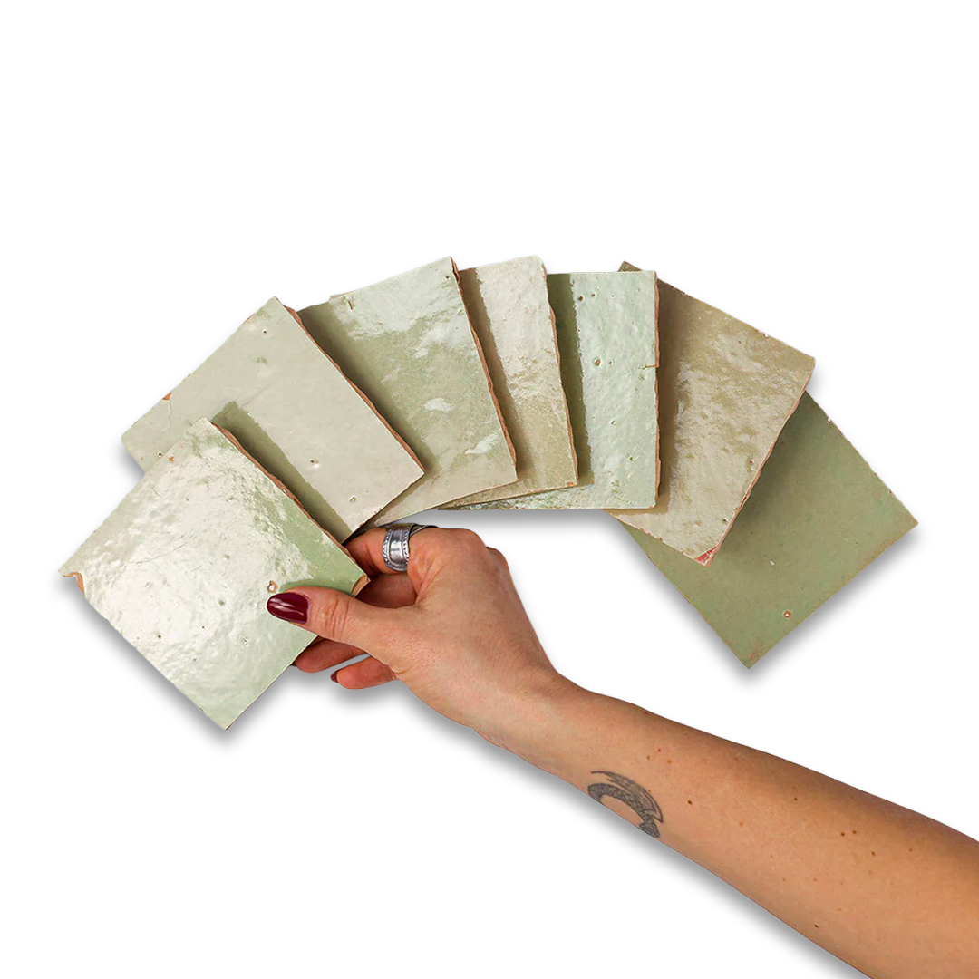 Hand holding a set of green stone samples against a white background