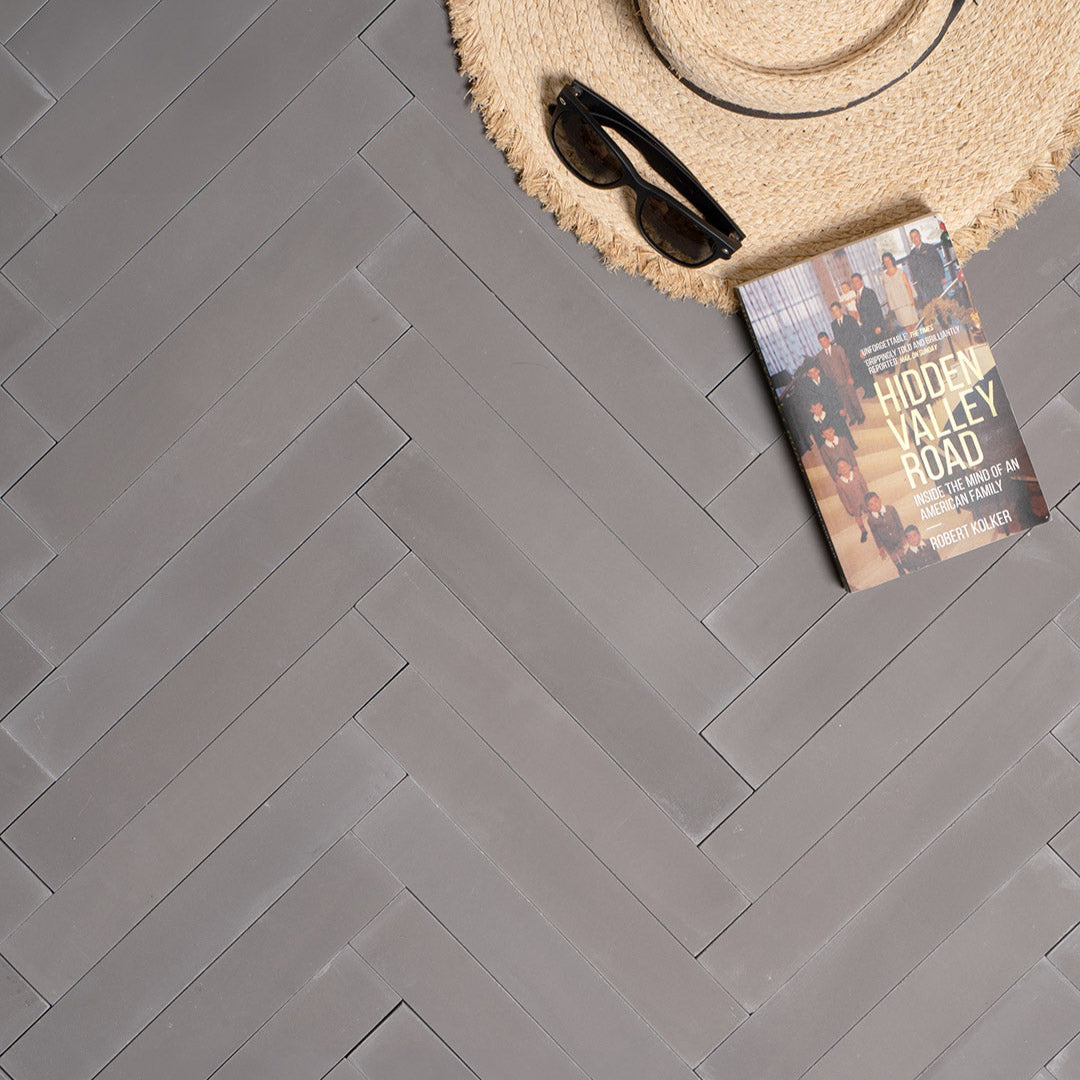 A chevron pattern in dark gray with a smooth matte finish, rectangular shape, ideal for modern, industrial, or minimalist flooring and wall design applications.
