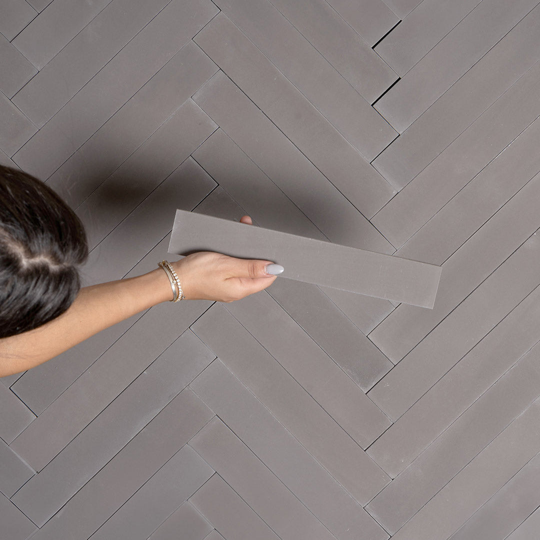 A chevron pattern in dark gray with a smooth matte finish, rectangular shape, ideal for modern, industrial, or minimalist flooring and wall design applications.