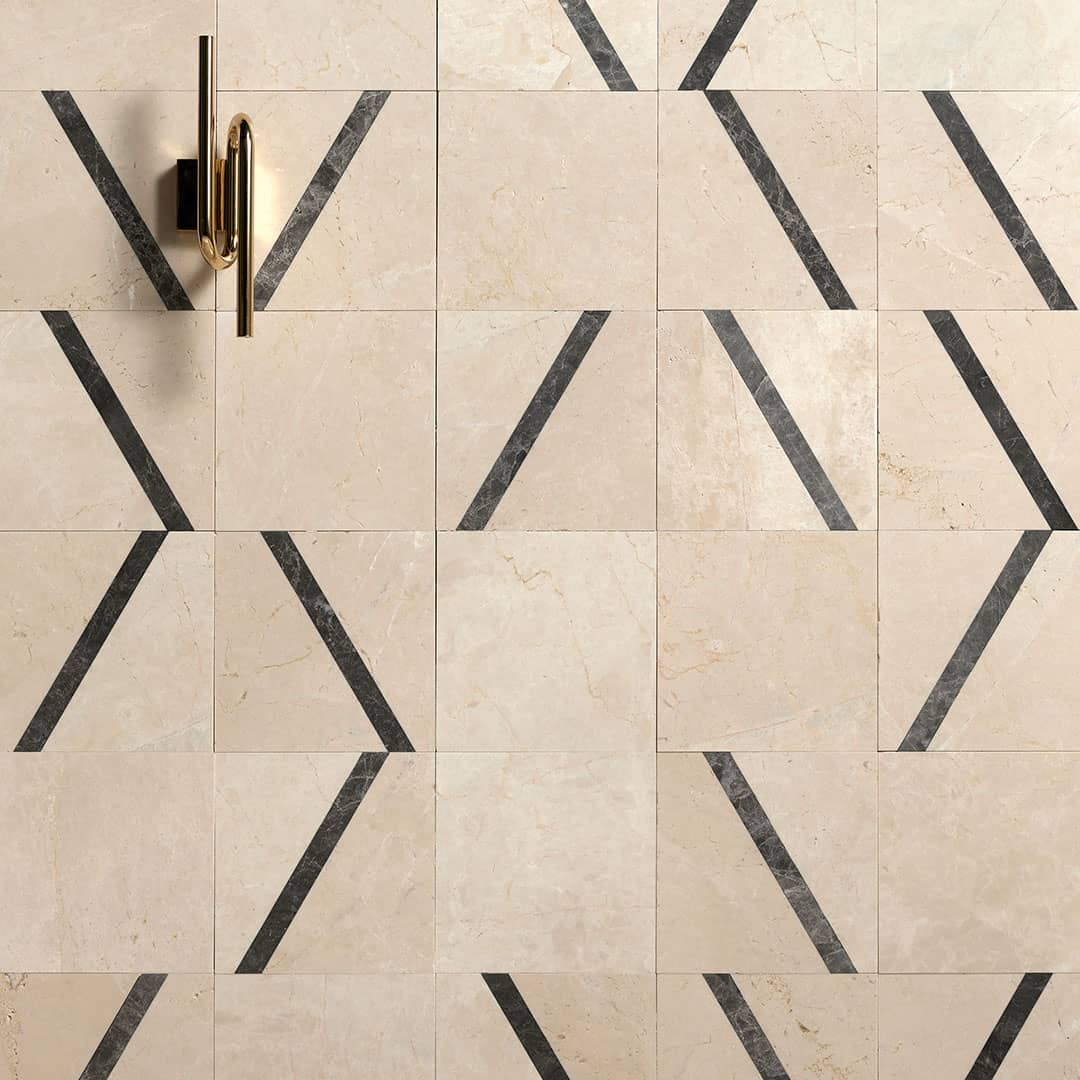 Beige tiles with black geometric patterns and a gold handle on a wall.
