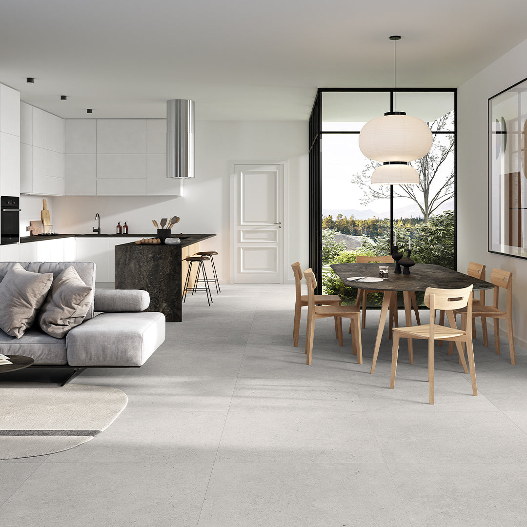 Modern living room with gray sofa, kitchen, and dining area.