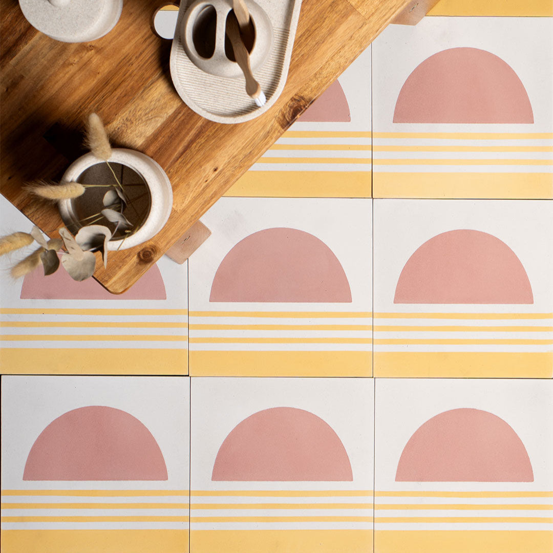 Square cement tile featuring a minimalist sunset design with a pink semicircle sun above soft yellow horizontal stripes, matte finish, ideal for modern, coastal, or bohemian interior wall and floor décor.