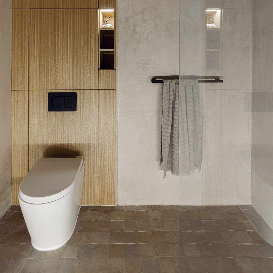 Modern bathroom with a toilet, towel rack, and tiled walls.