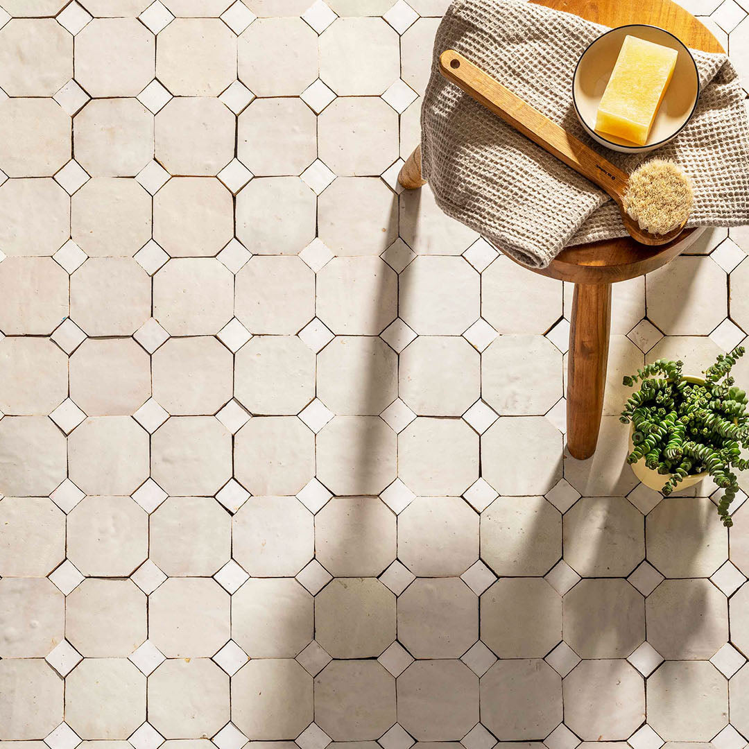 Hexagonal tile pattern on a floor with a wooden stool and plant in the background
