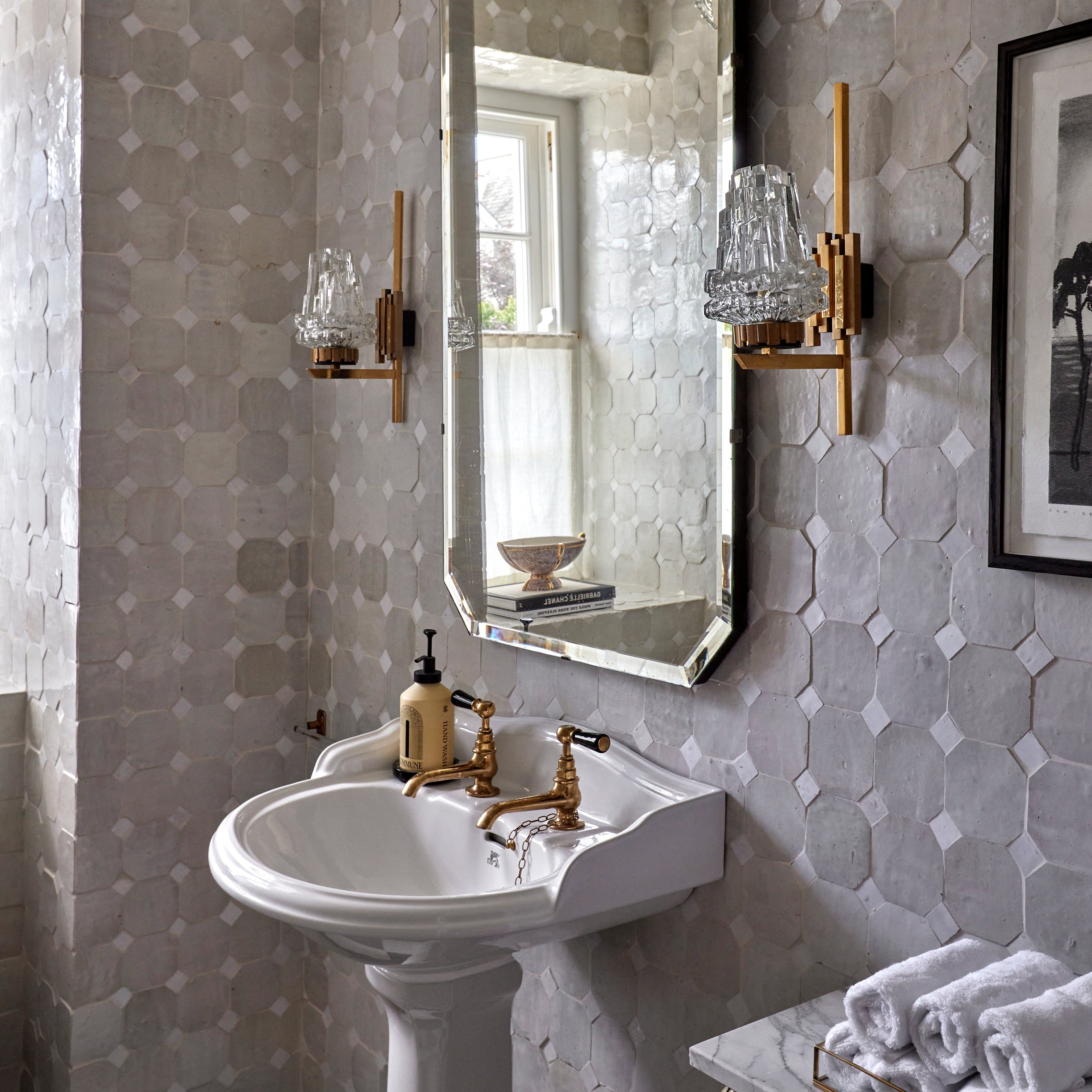 Bathroom with hexagonal tiles, a sink, and decorative mirror.