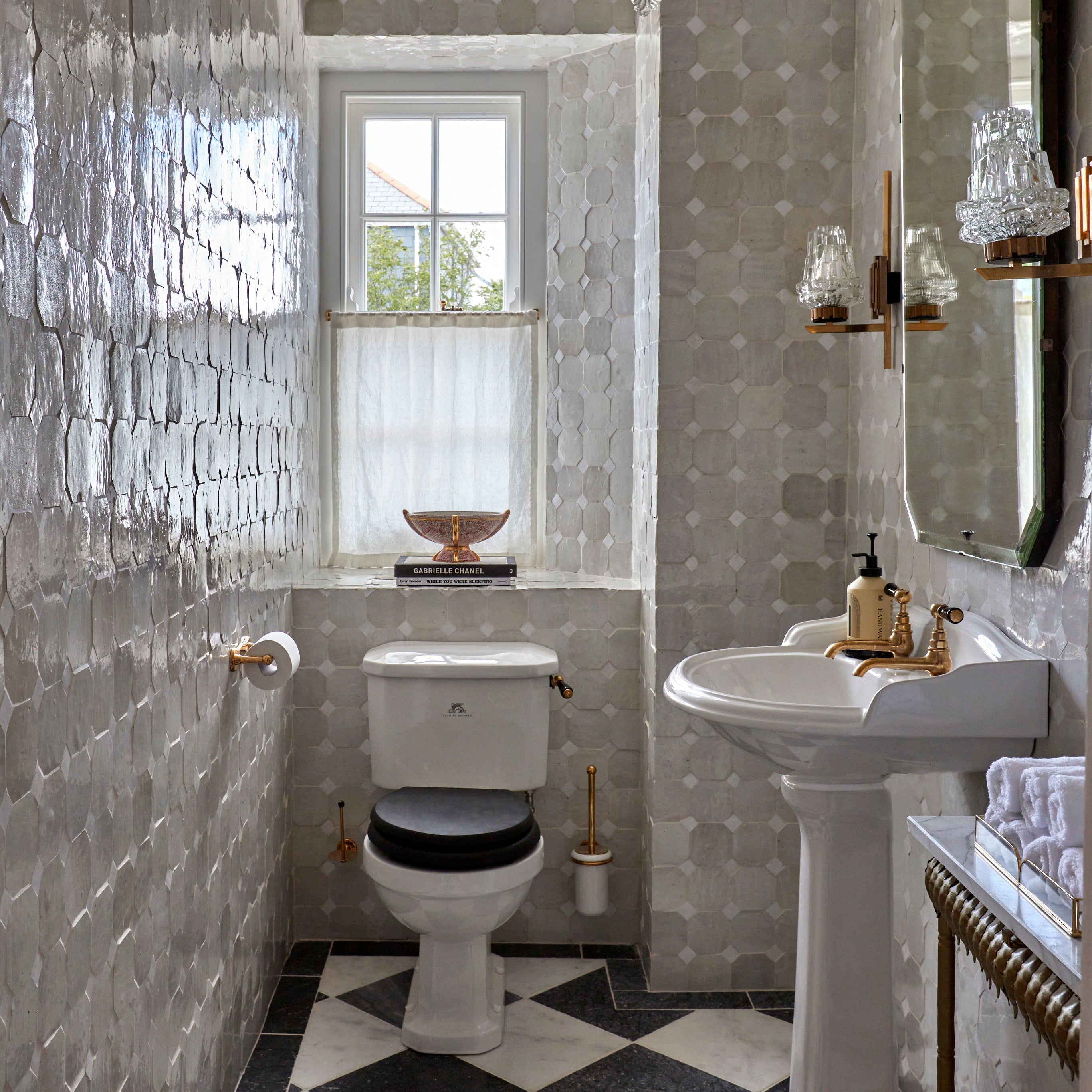 Bathroom with tiled walls, a toilet, sink, and decorative elements.