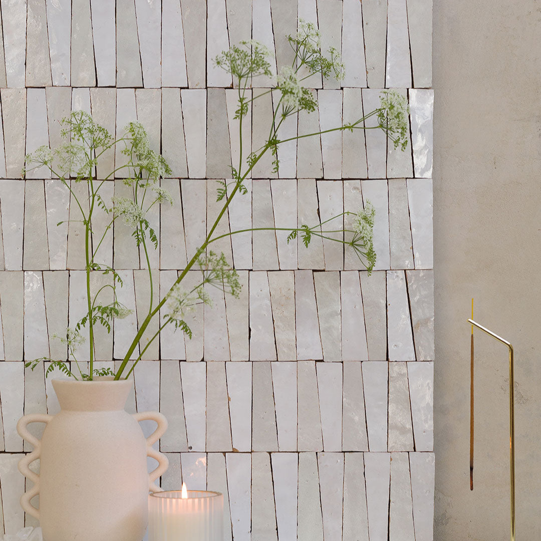 Decorative wall with vertical slats and a vase with plants in front