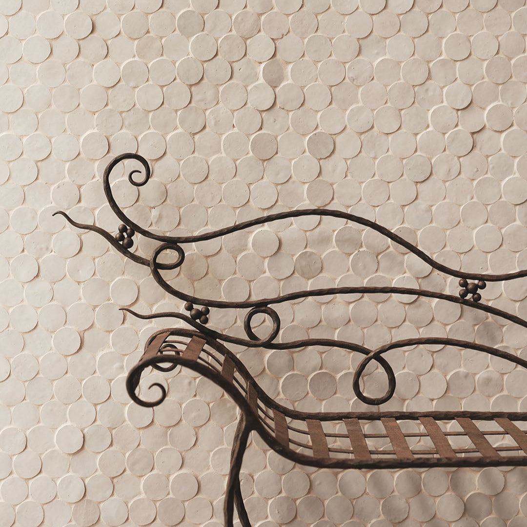 Decorative metal bench against a tiled wall with a circular tile pattern