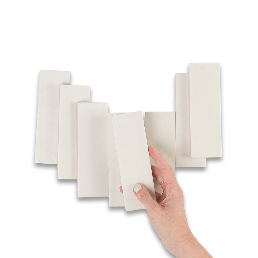 Hand holding a stack of white pads against a white background