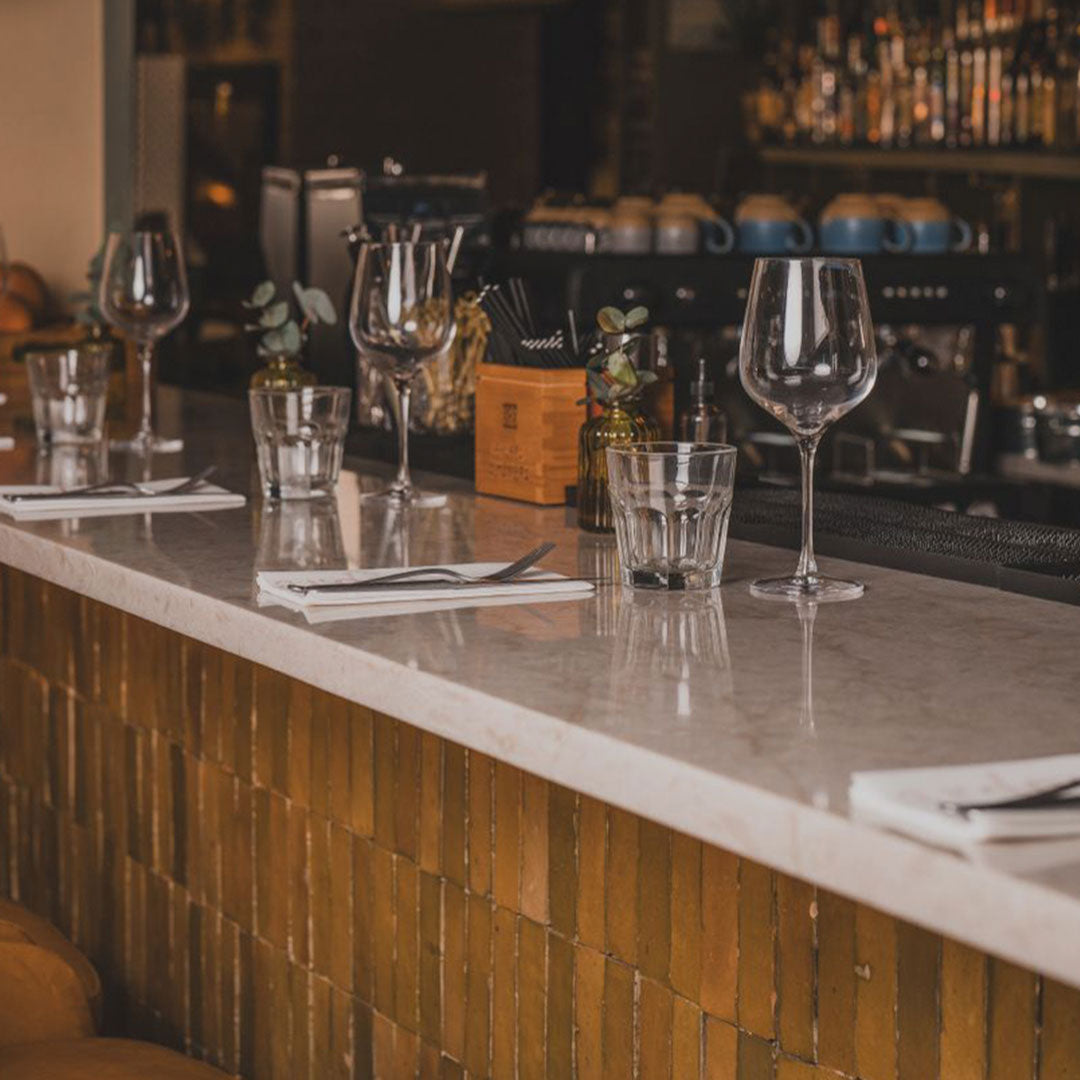 Bar counter with wine glasses and bottles in a dimly lit bar setting