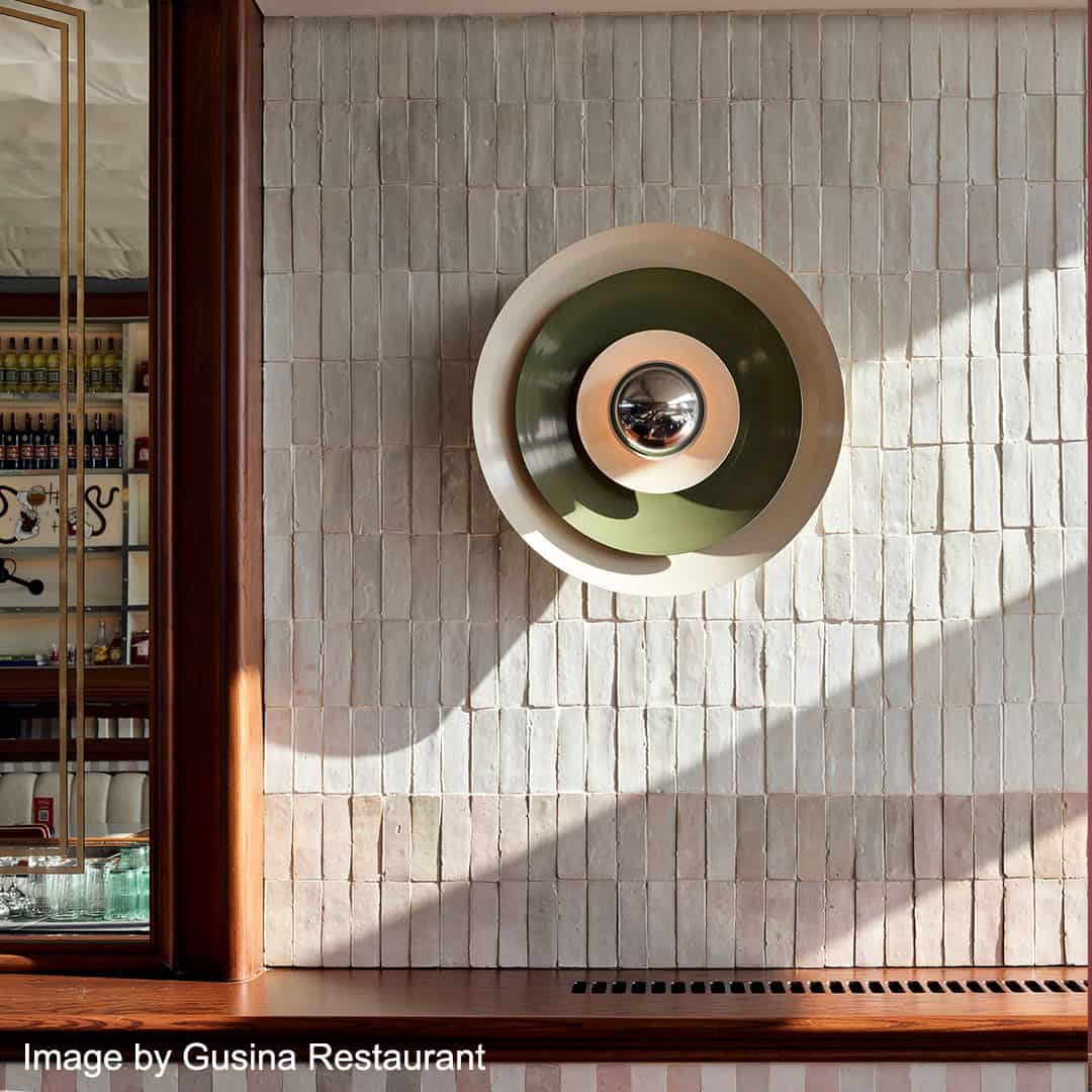 Decorative wall light fixture on a tiled wall with a restaurant setting in the background